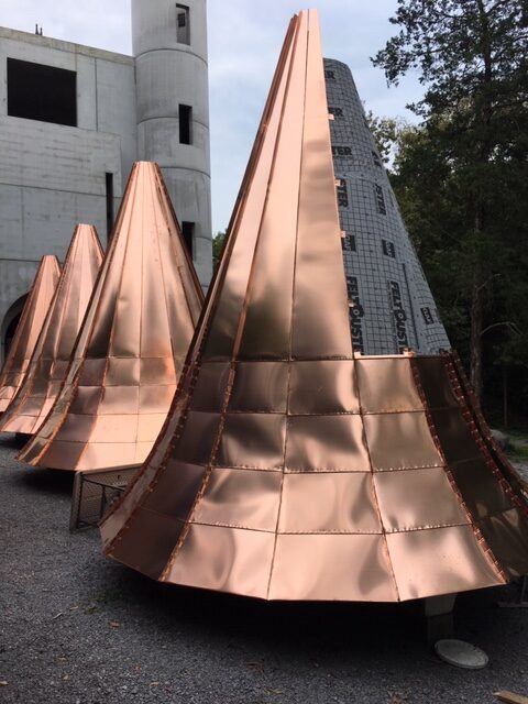 A row of copper tents lined up in front of a building.