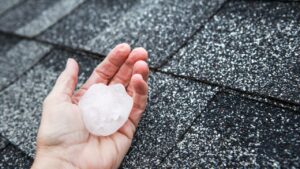 Large piece of hail in a man's hand during a roof inspection