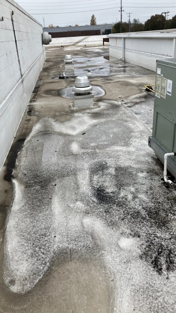 Old deteriorated commercial flat roof that needs replacement - MidSouth Construction LLC Image of a deteriorated commercial roof that needs to be replaced