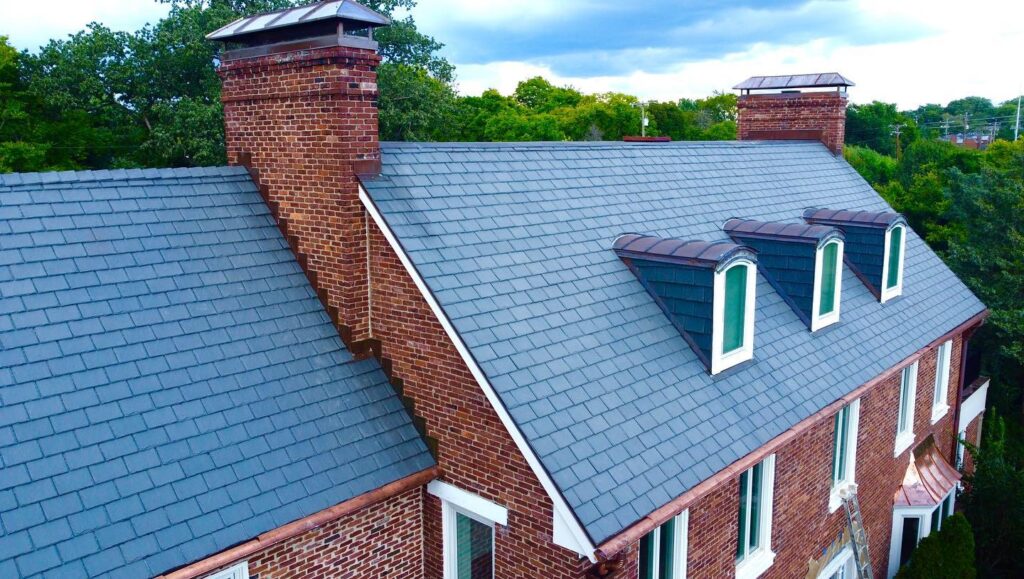 Large brick house with faux slate roof in gray.